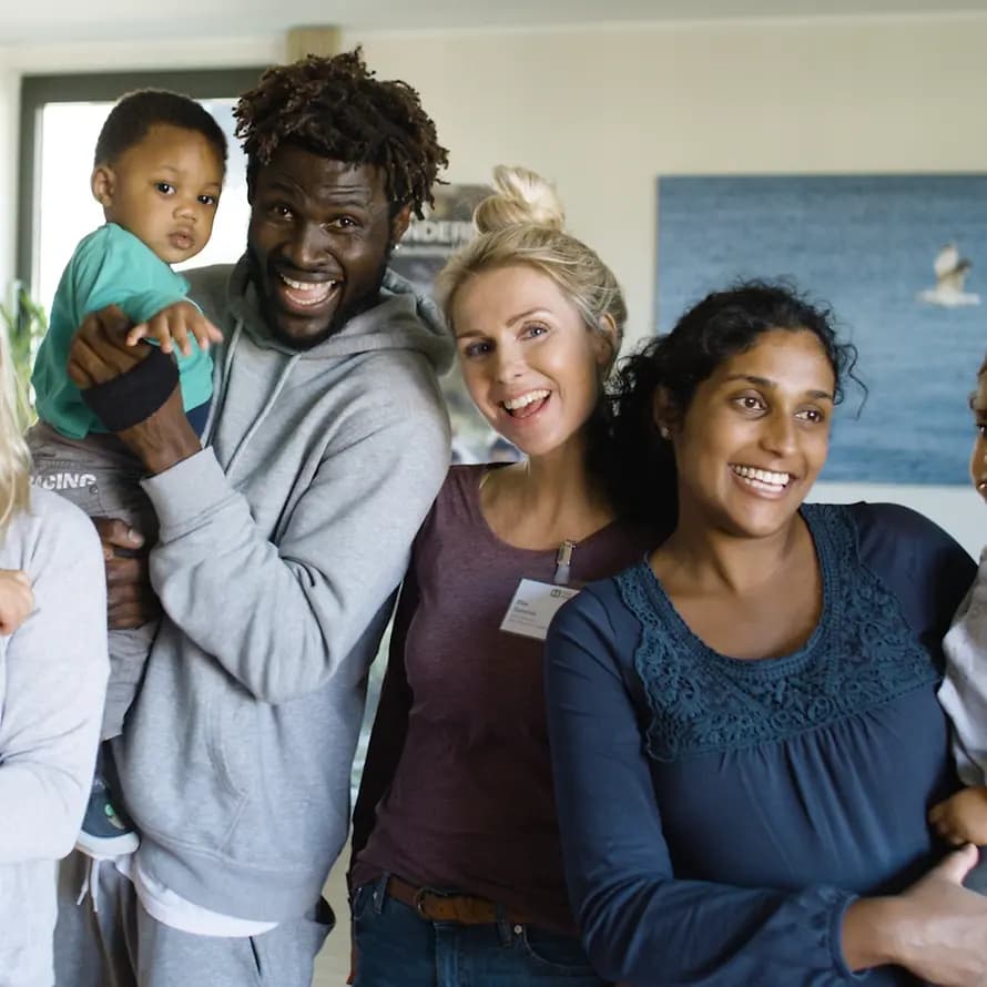 SOS-Familienzentrum Frauen, Kinder und ein Mann aus dem SOS-Familienzentrum lachen in die Kamera