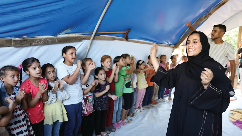 100887_SOS-Kinderdorf Palästina_Freizeit im Camp (14).Jpg Kinder stehen in einer Reihe in Zelt im SOS-Camp in Gaza und klatschen, Betreuerin macht es vor.